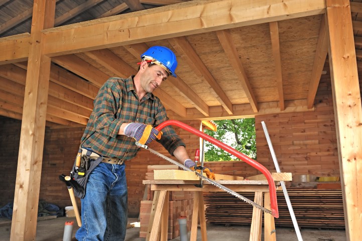 Ein Mann sägt Holz beim Hausbauen